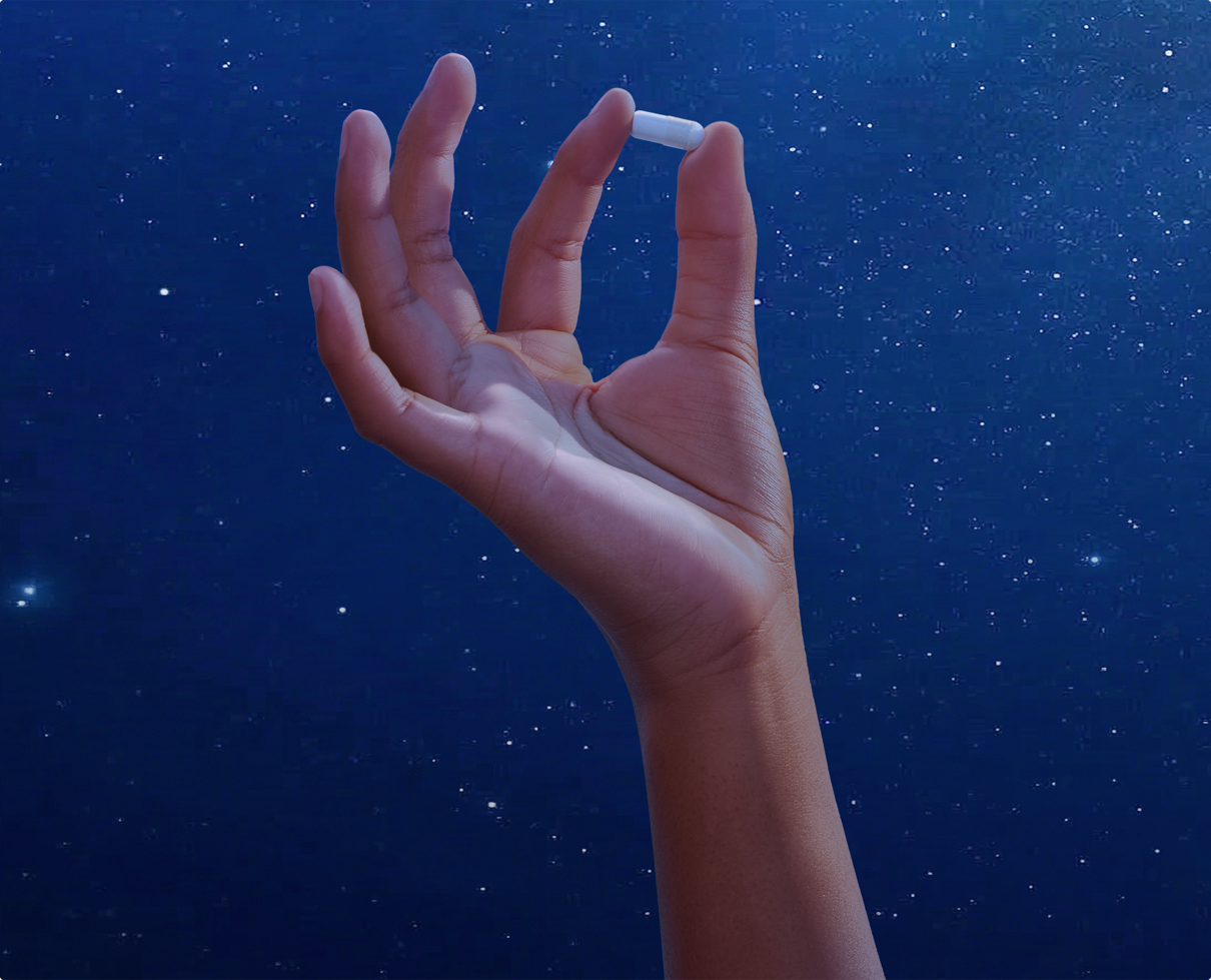 Hand holding a Stasis Kids gummy against a starry night sky